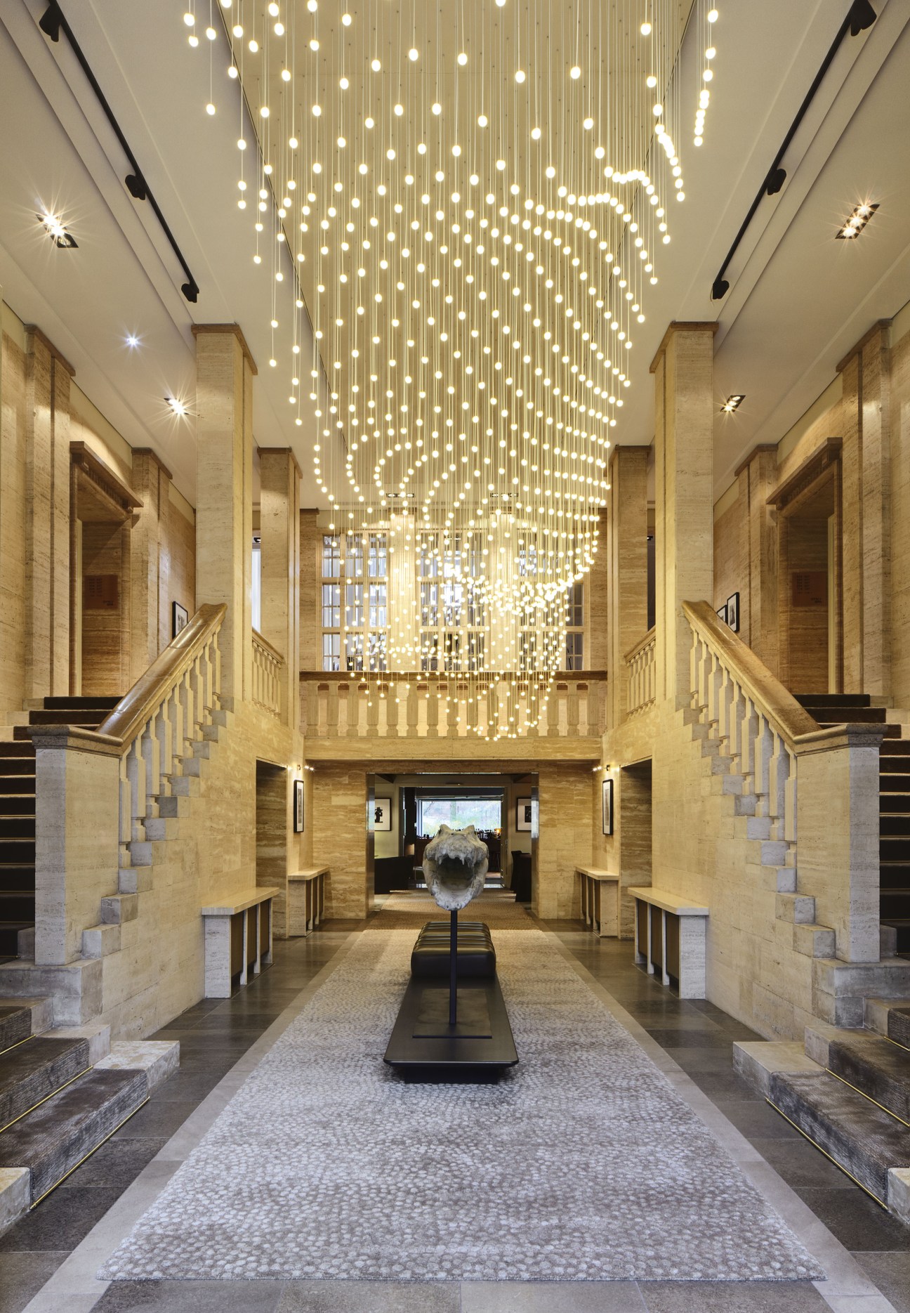 Das Stue hotel lobby with suspended pendant lights and symmetrical staircases.