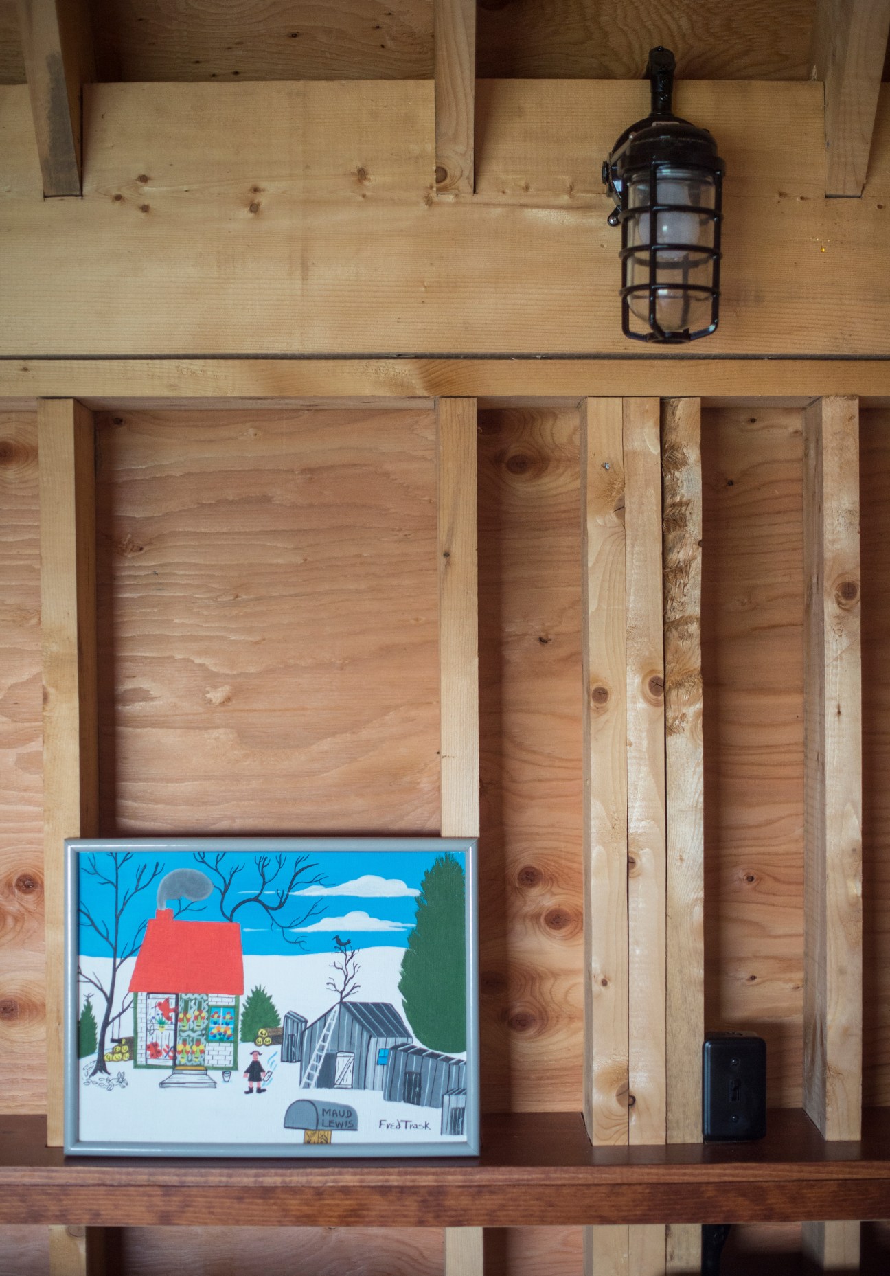 Colorful folk art painting displayed on wooden shelving in rustic interior