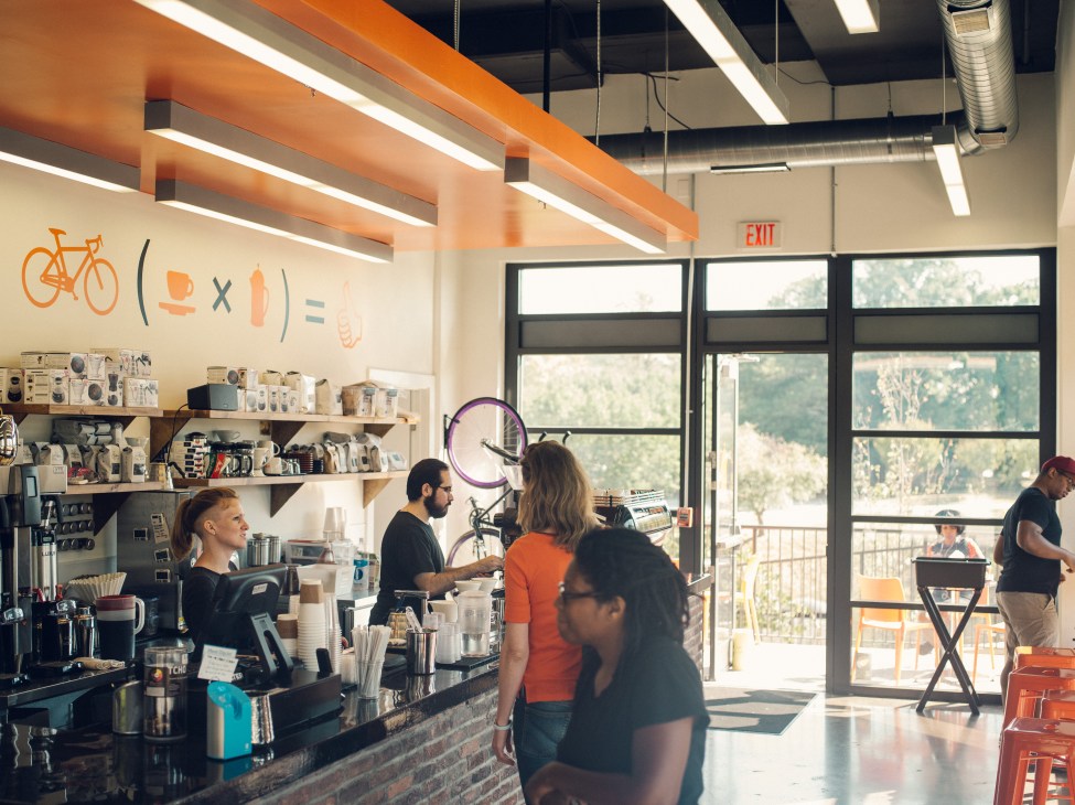 Interior of Filter Coffeehouse in Washington with orange beams, customers at counter, and bicycle displayed on wall.
