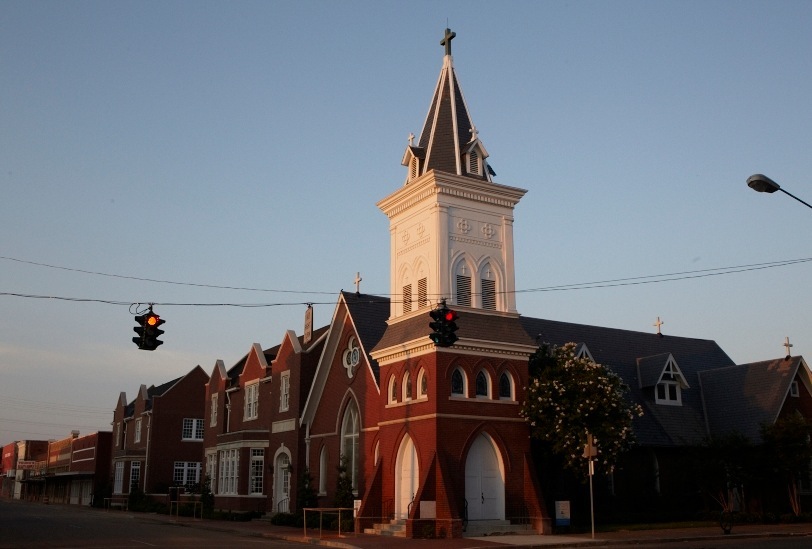 Greenwood's Episcopal Church, a red brick building with a tall white steeple topped with a cross.
