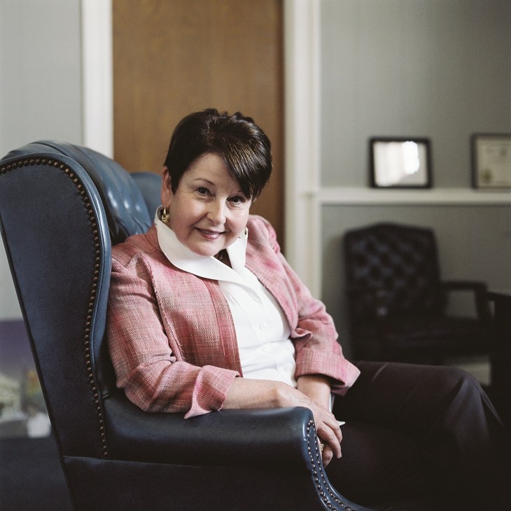 Carolyn McAdams, Greenwood's mayor, seated in a blue leather chair wearing a pink blazer and white blouse.