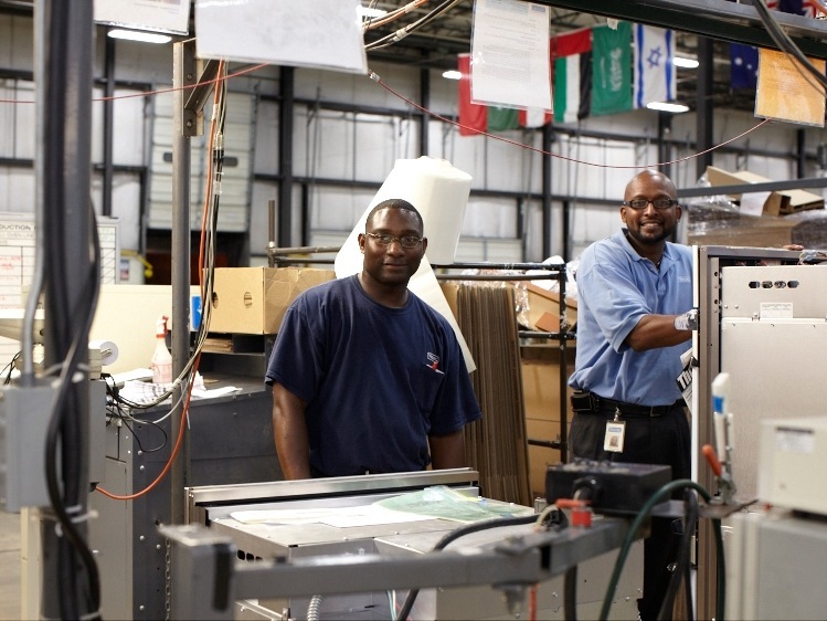 Two Viking factory workers assemble kitchen range components on a manufacturing line.