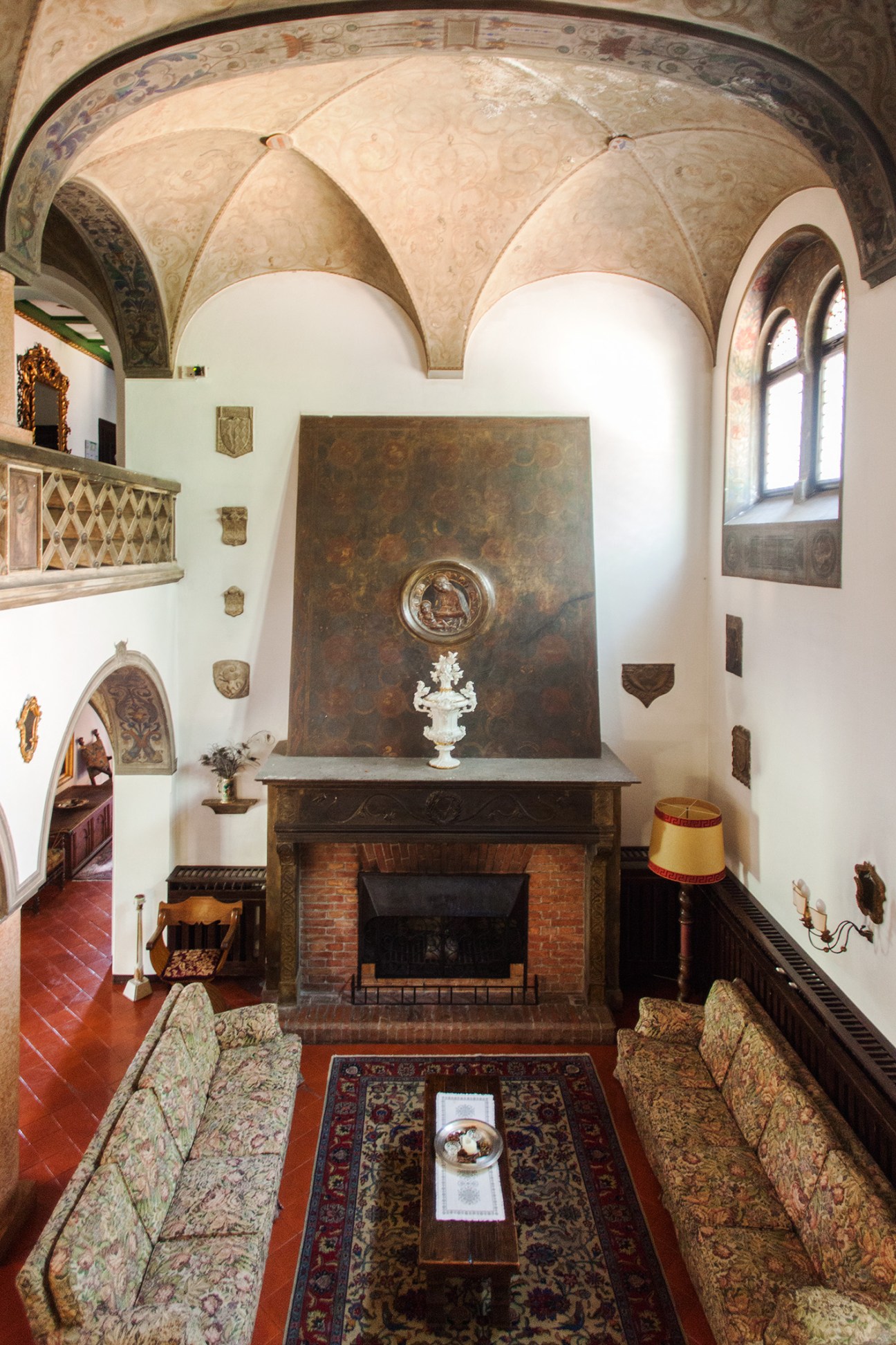 Castle parlour room with vaulted ceilings, brick fireplace, and period furnishings.