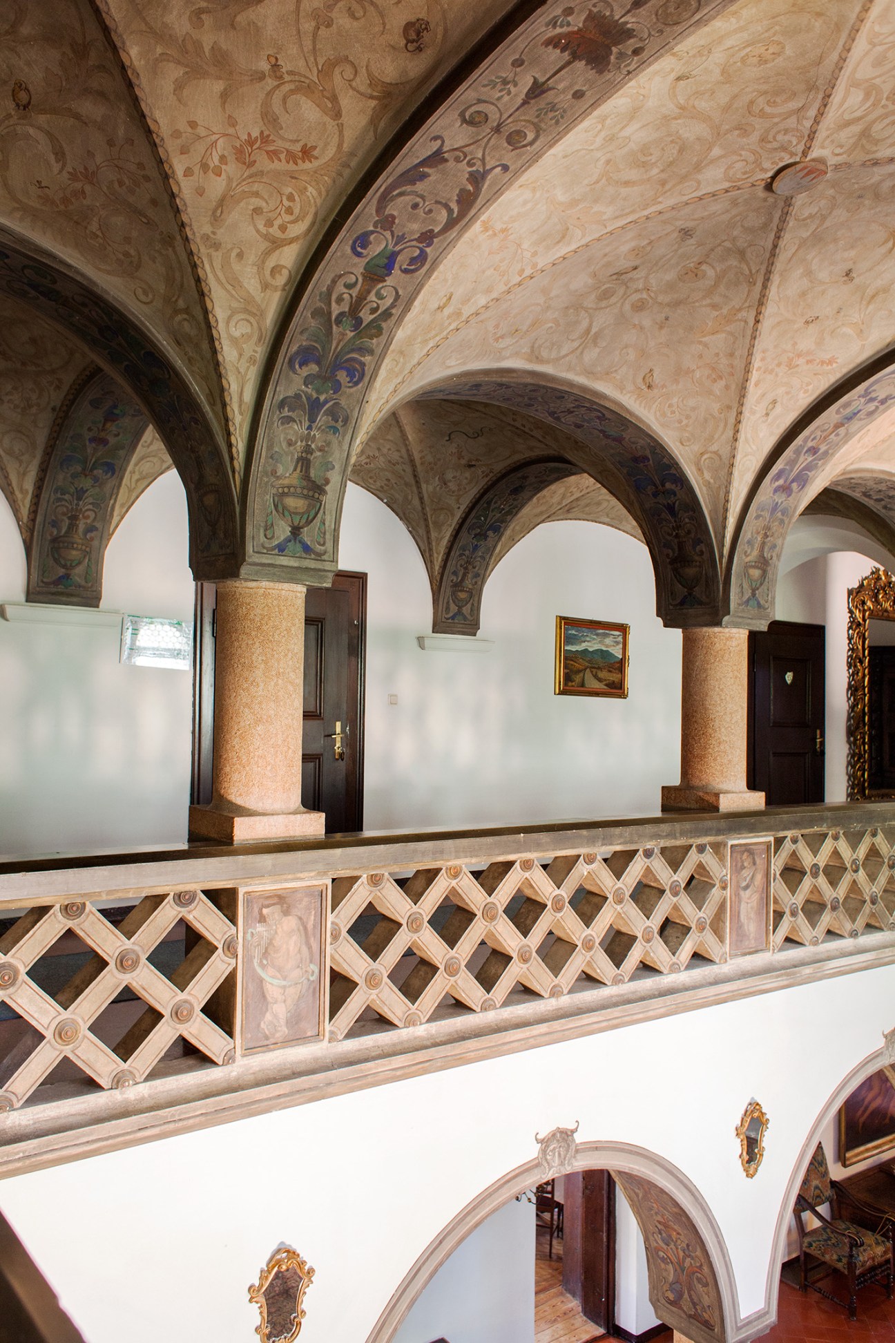 Renaissance-style vaulted arches with frescoed decorations and ornate balustrade in Castello Stifterhof's parlour.