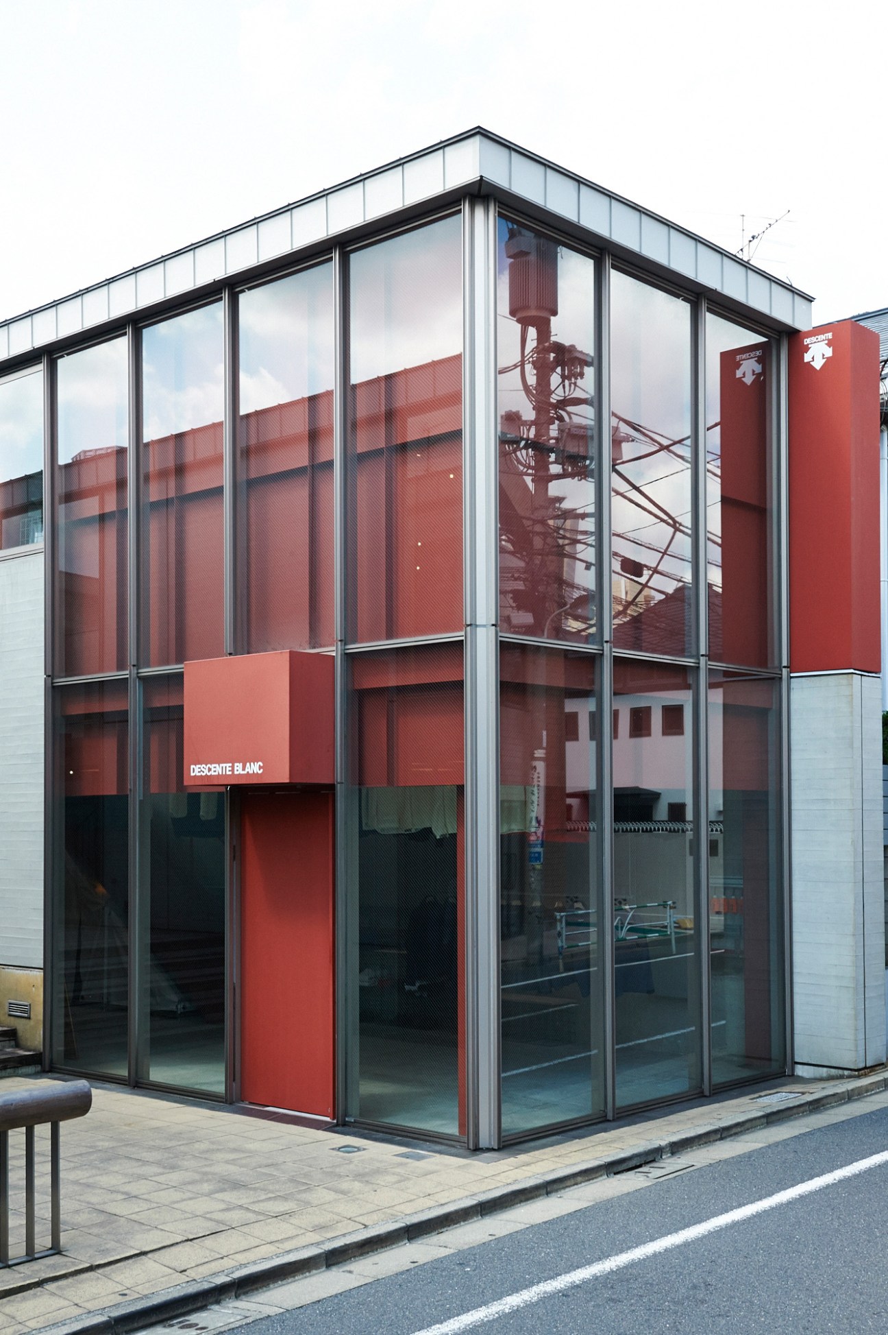 Modern Descente Blanc storefront with red and black facade, large glass windows, and metal framing.
