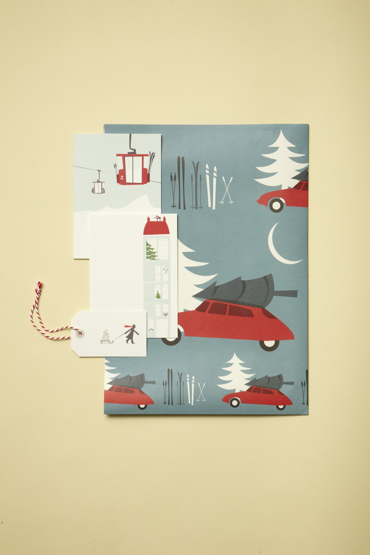 Pleased To Meet wrapping paper and gift tag with winter motifs including cars, trees, and festive illustrations.