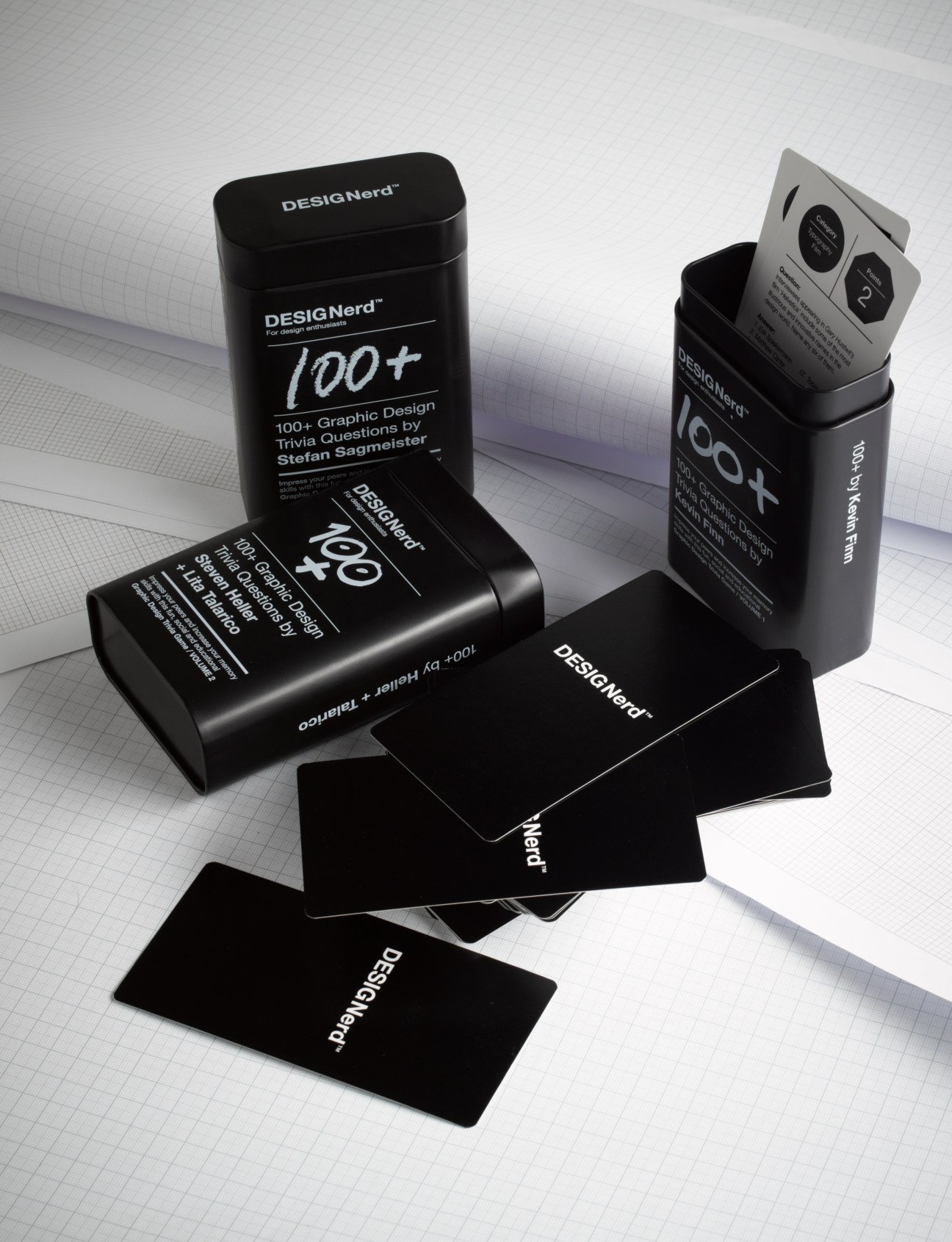 DesignNerd trivia card game set with black boxes and cards displayed on grid paper background.