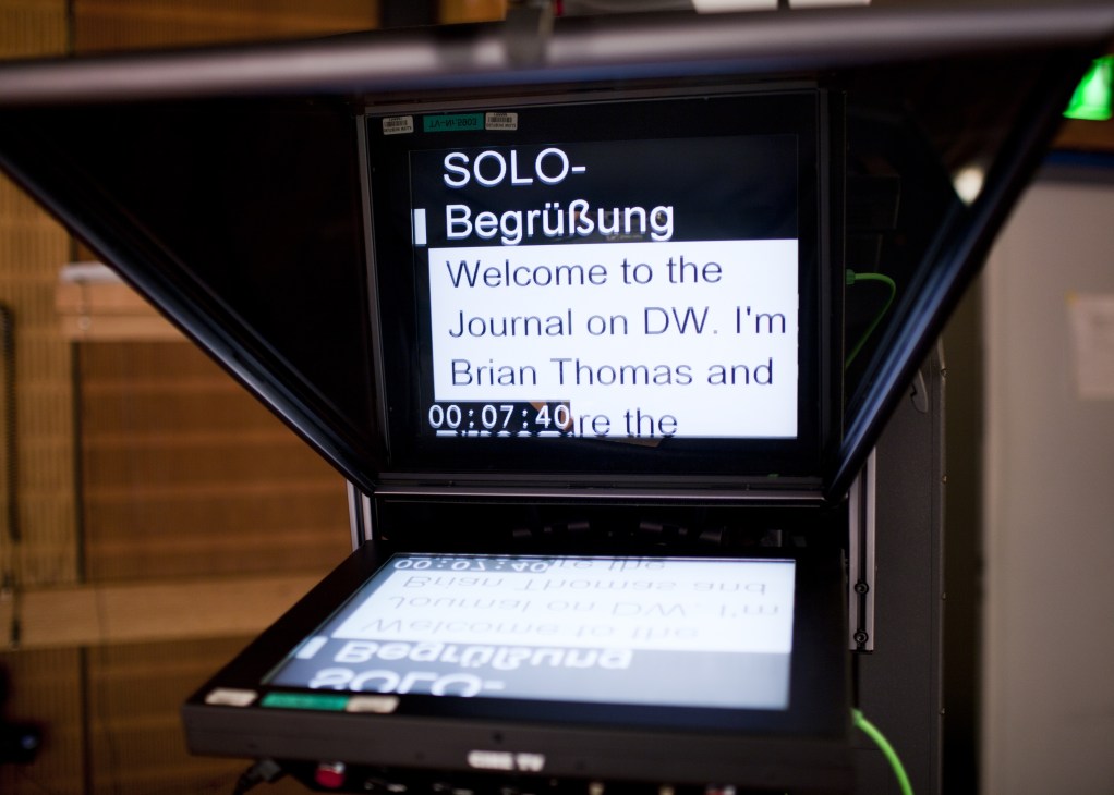 Autocue screen displaying text for DW's Journal news programme with German and English text visible.