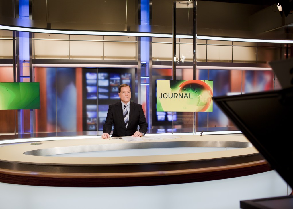 News anchor Dirk Jacobs at desk in Deutsche Welle Journal studio during live broadcast.