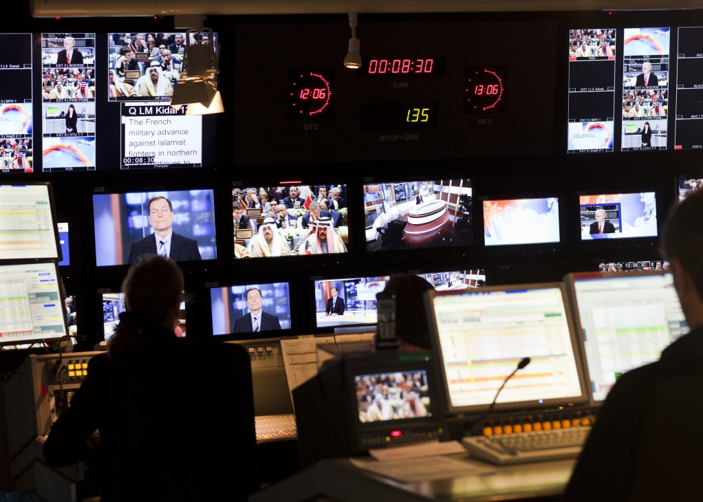 Deutsche Welle control room with multiple broadcast monitors and timers displaying news programming.