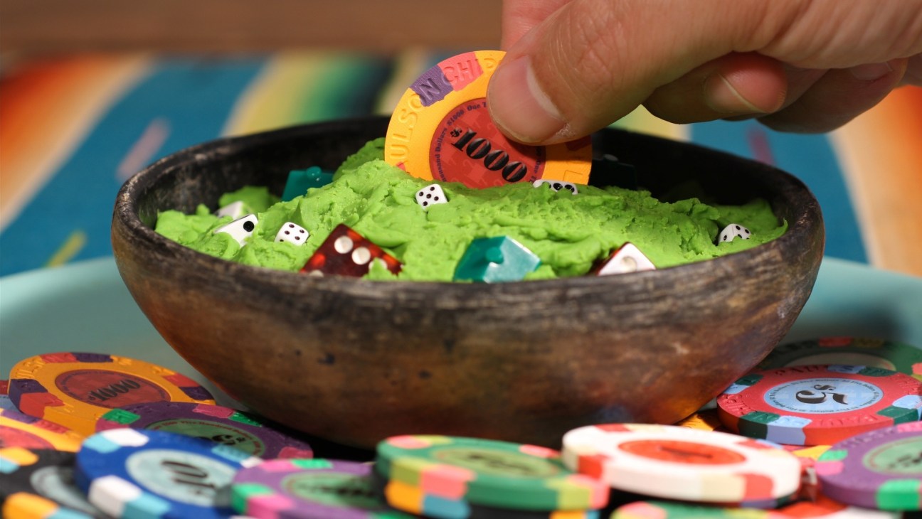 Stop-frame animation showing green guacamole in a wooden bowl with poker chips and dice as props.
