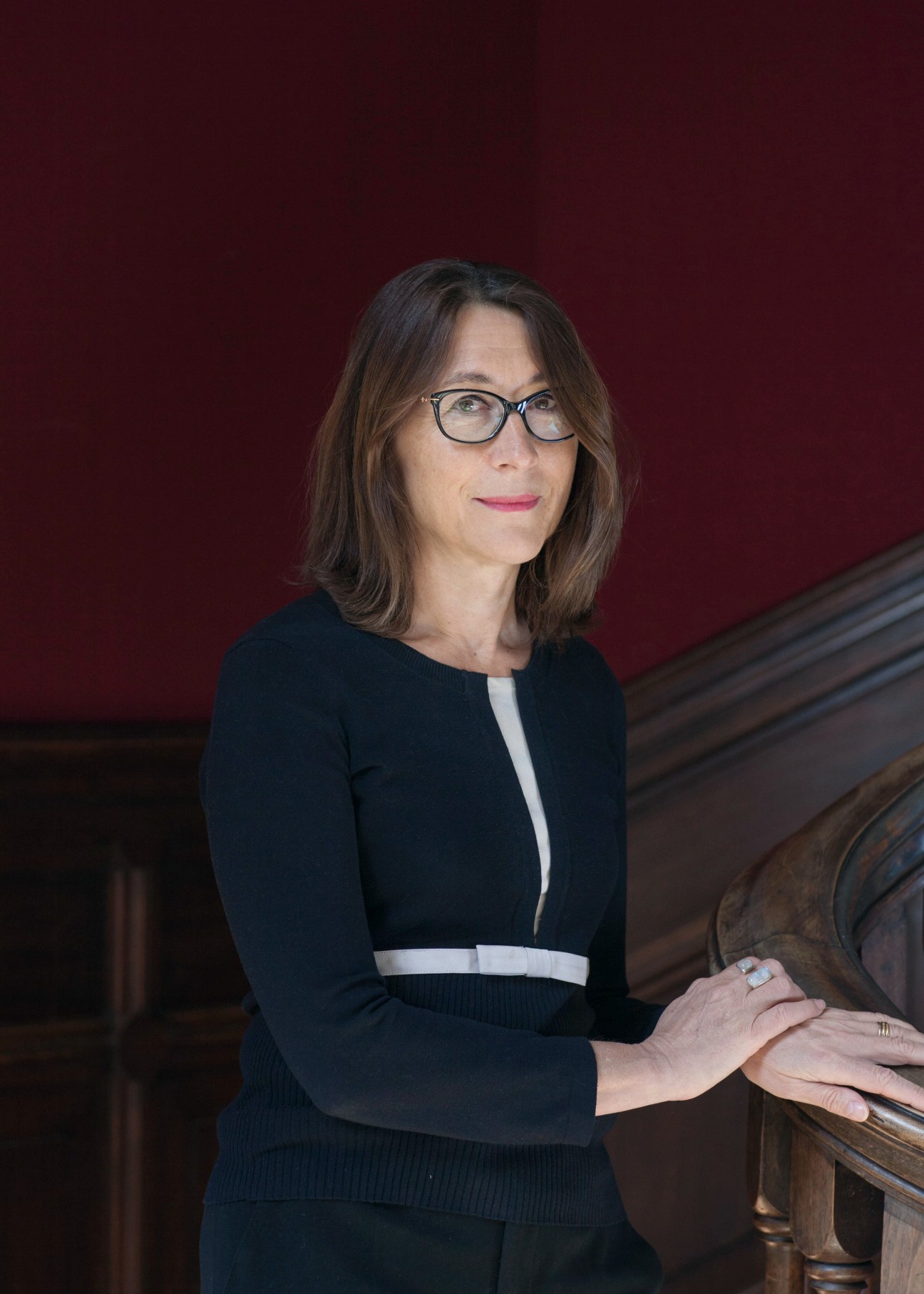 Carine Camby, managing director of Cité Internationale Universitaire de Paris, poses for a portrait against a deep red wall.
