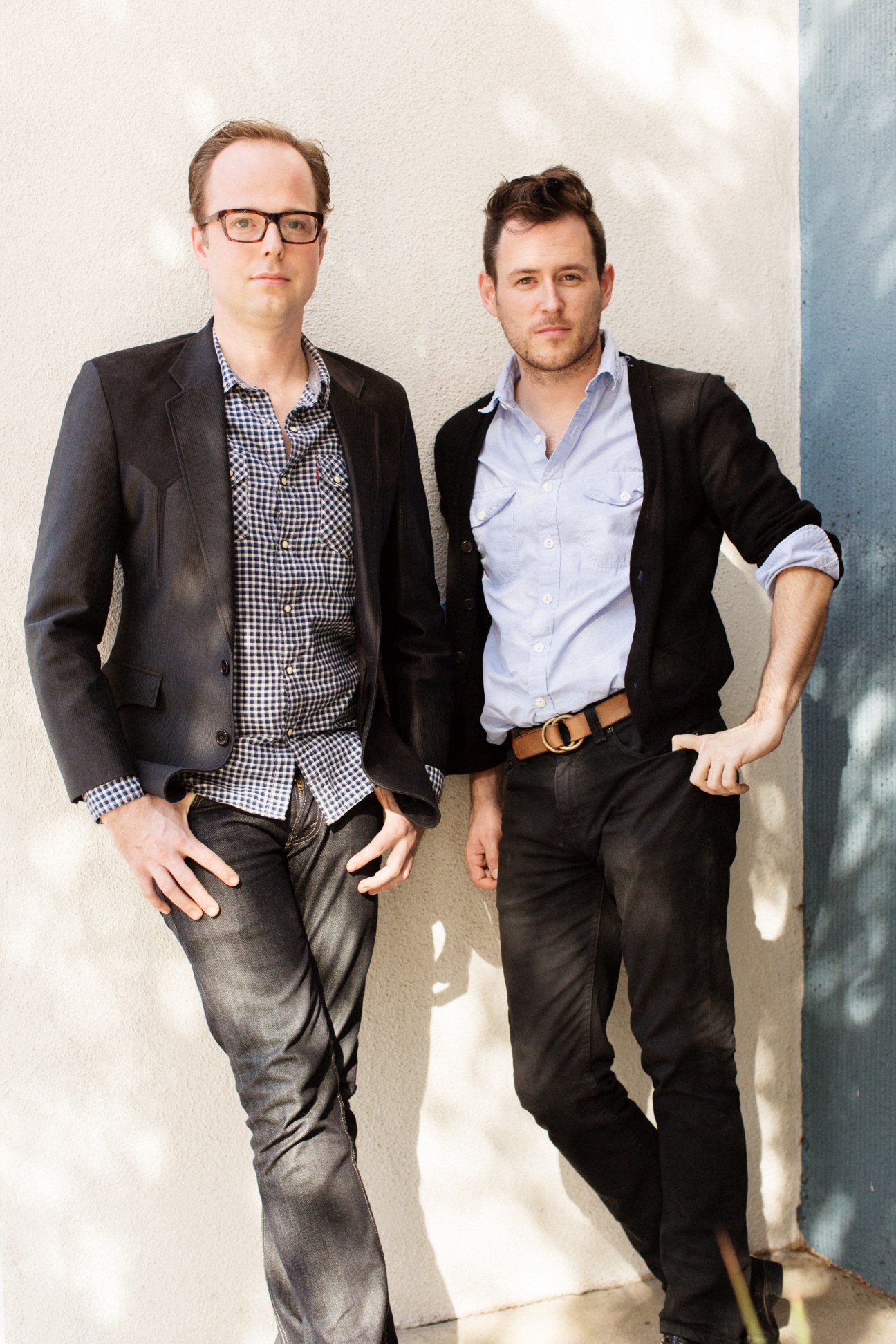 Two men in business casual attire standing against a white wall, representing Dirty Robber film and TV production founders.
