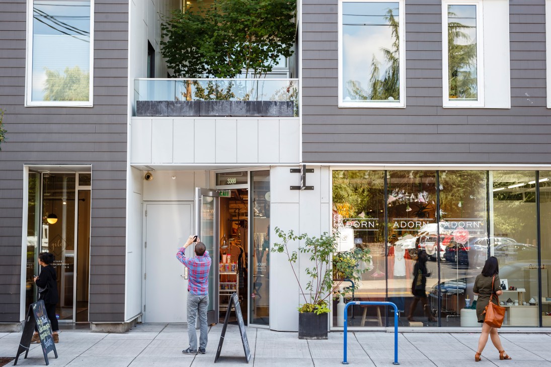 Street-level view of Adorn womenswear shop storefront on Portland's Division Street with large windows and modern facade.
