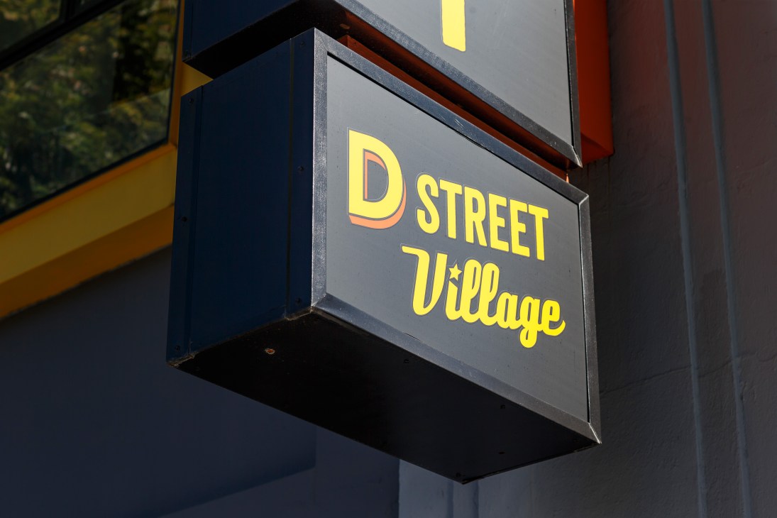 D Street Village storefront sign with yellow lettering on dark background