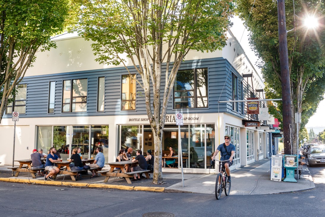 Imperial Shop and Taproom craft-beer venue with outdoor seating and cyclist on Division Street, Portland.