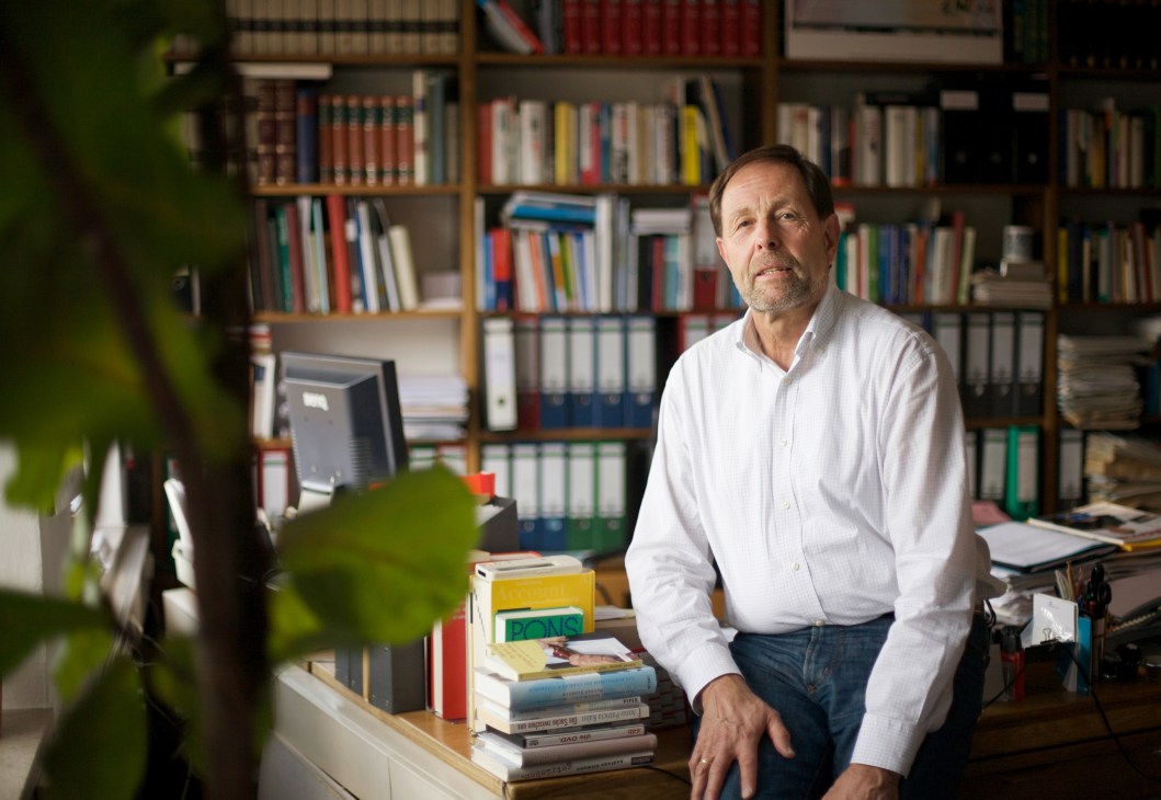 Ulrich Brenner, director of the Deutsche Journalistenschule, seated at his desk in his Munich office with bookshelves behind him.