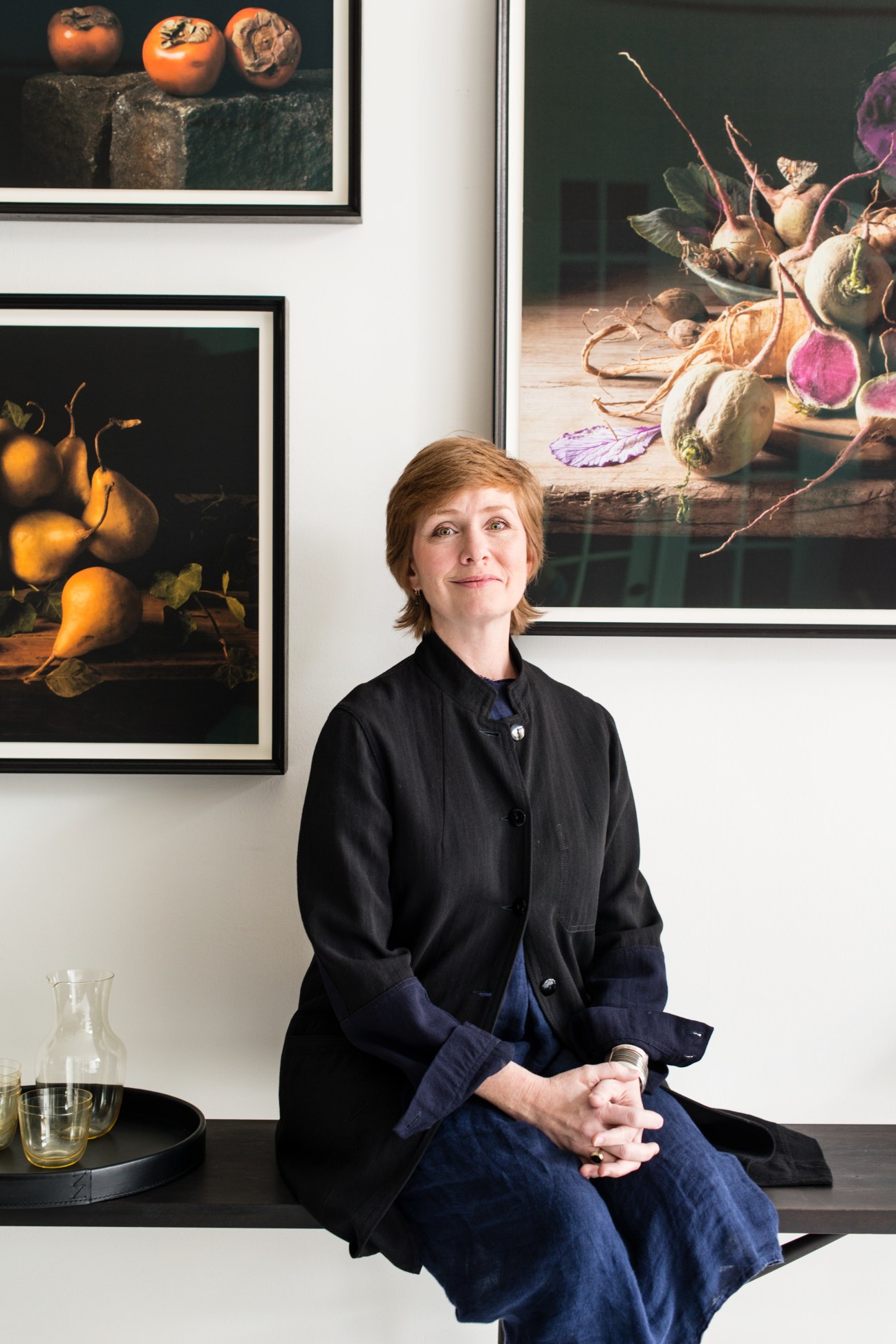 Sam Hamilton, founder of March design store, sits in front of framed food photography on white walls.