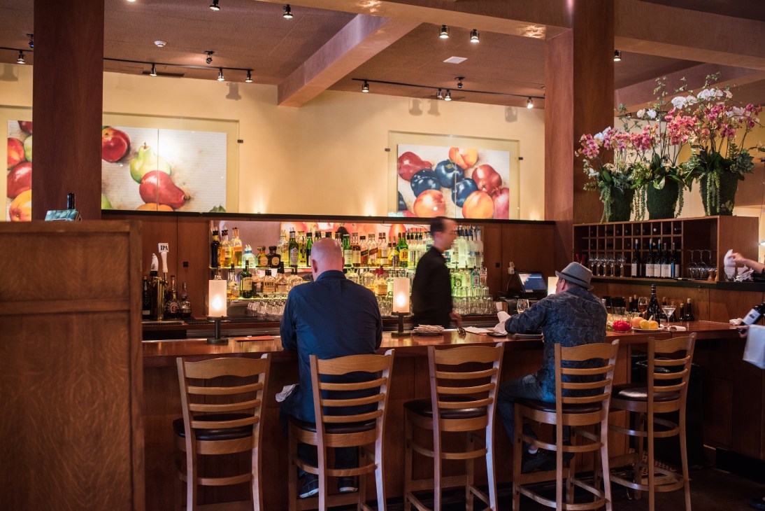 Diners seated at the wooden bar counter at Insalata's restaurant with bartenders working behind the counter.
