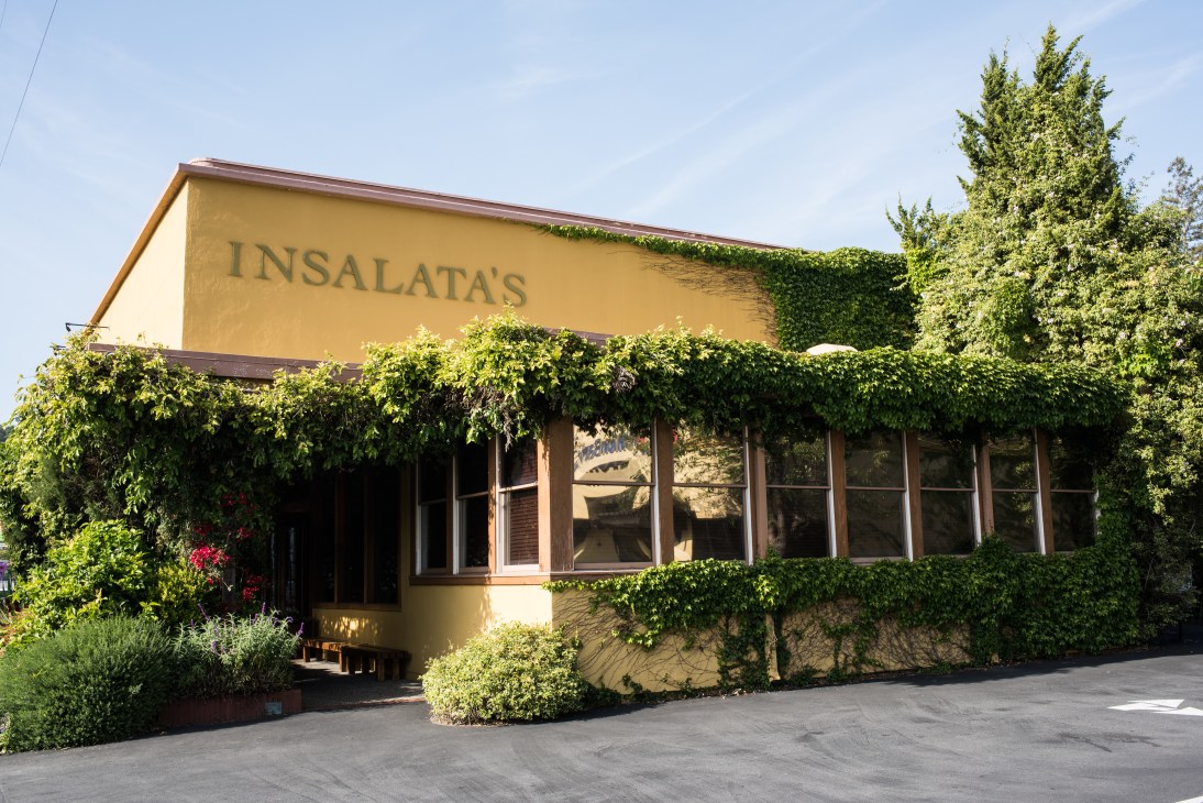 Exterior of Insalata's restaurant with yellow facade and ivy-covered walls.