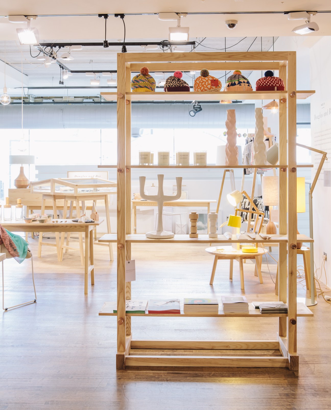 Interior of Douglas and Bec design store showing wooden display shelving with colorful knit hats and home goods.