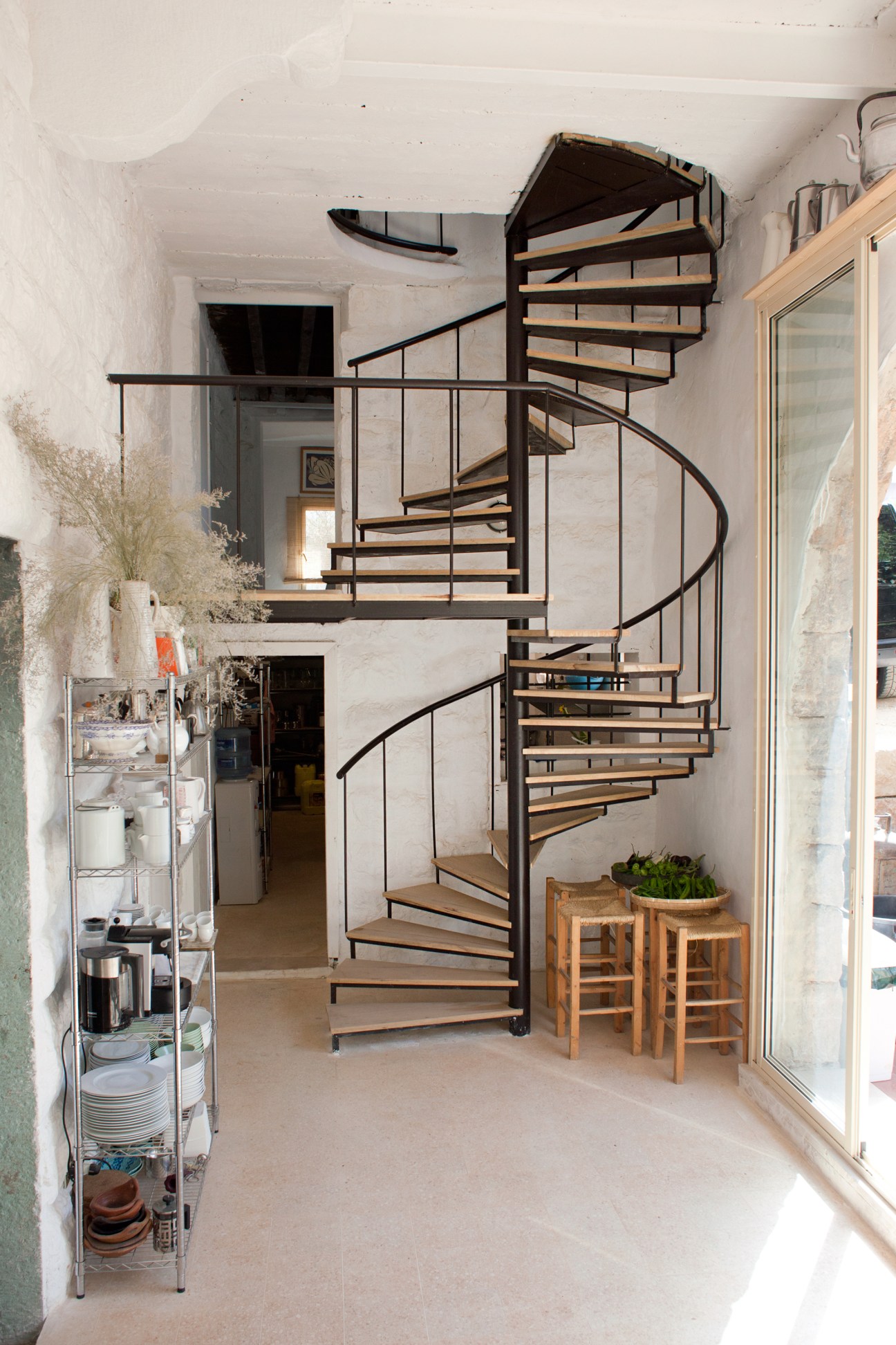 Modern black spiral staircase with wooden treads in white-walled interior of Beit Douma.