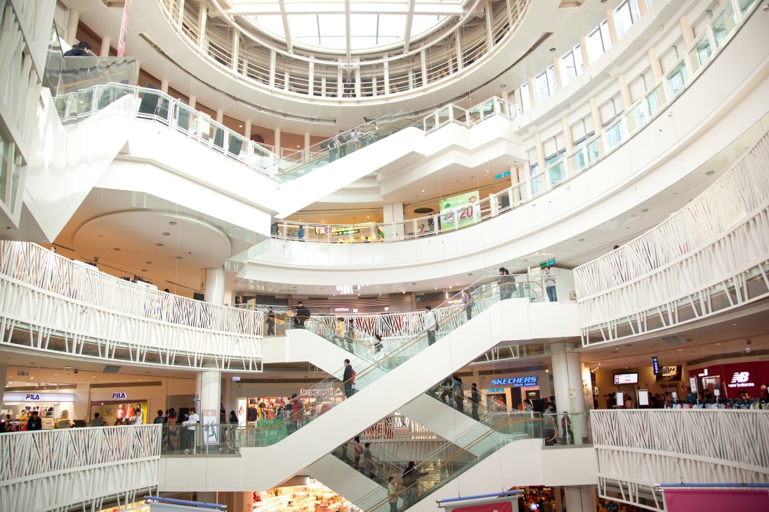 Interior view of Dream Mall in Kaohsiung showing multiple levels with escalators, retail storefronts and shoppers.