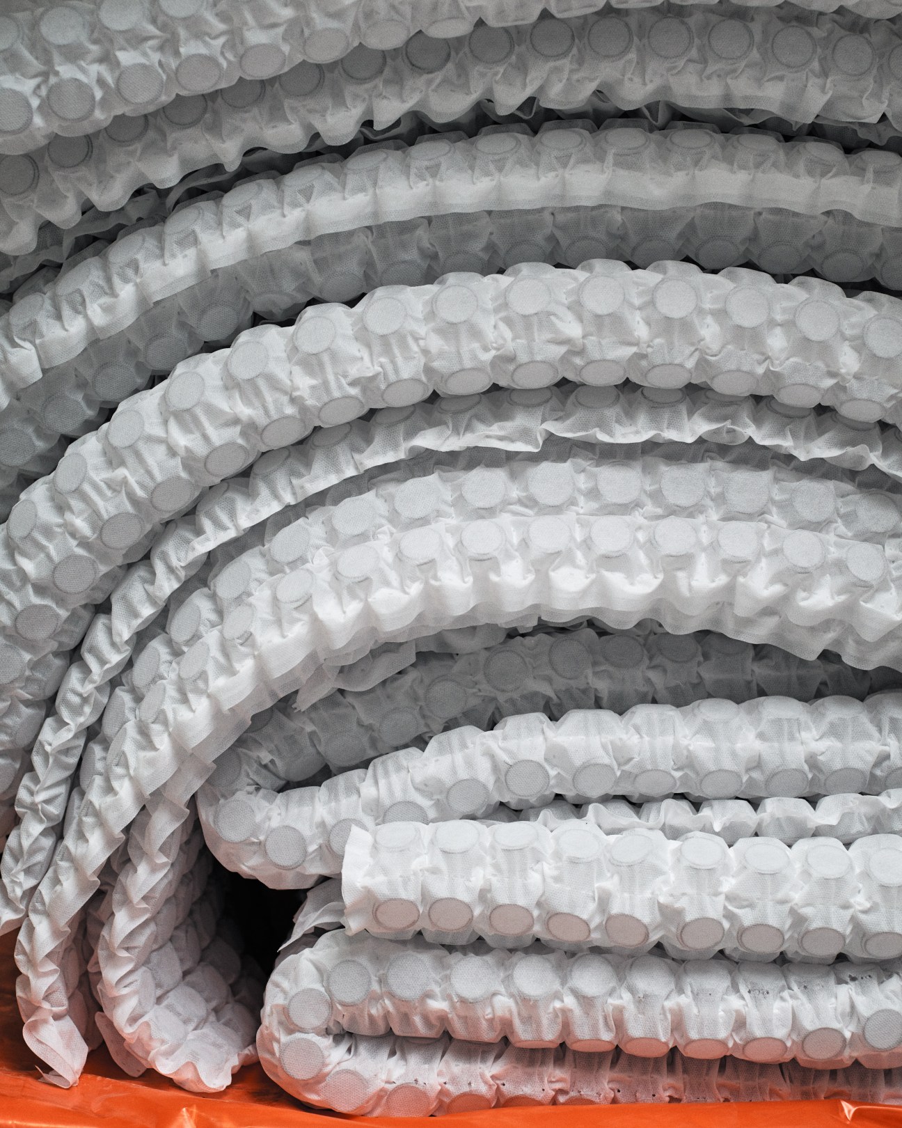 Stacked pocketed sheets with welded micro-springs ready for mattress assembly.