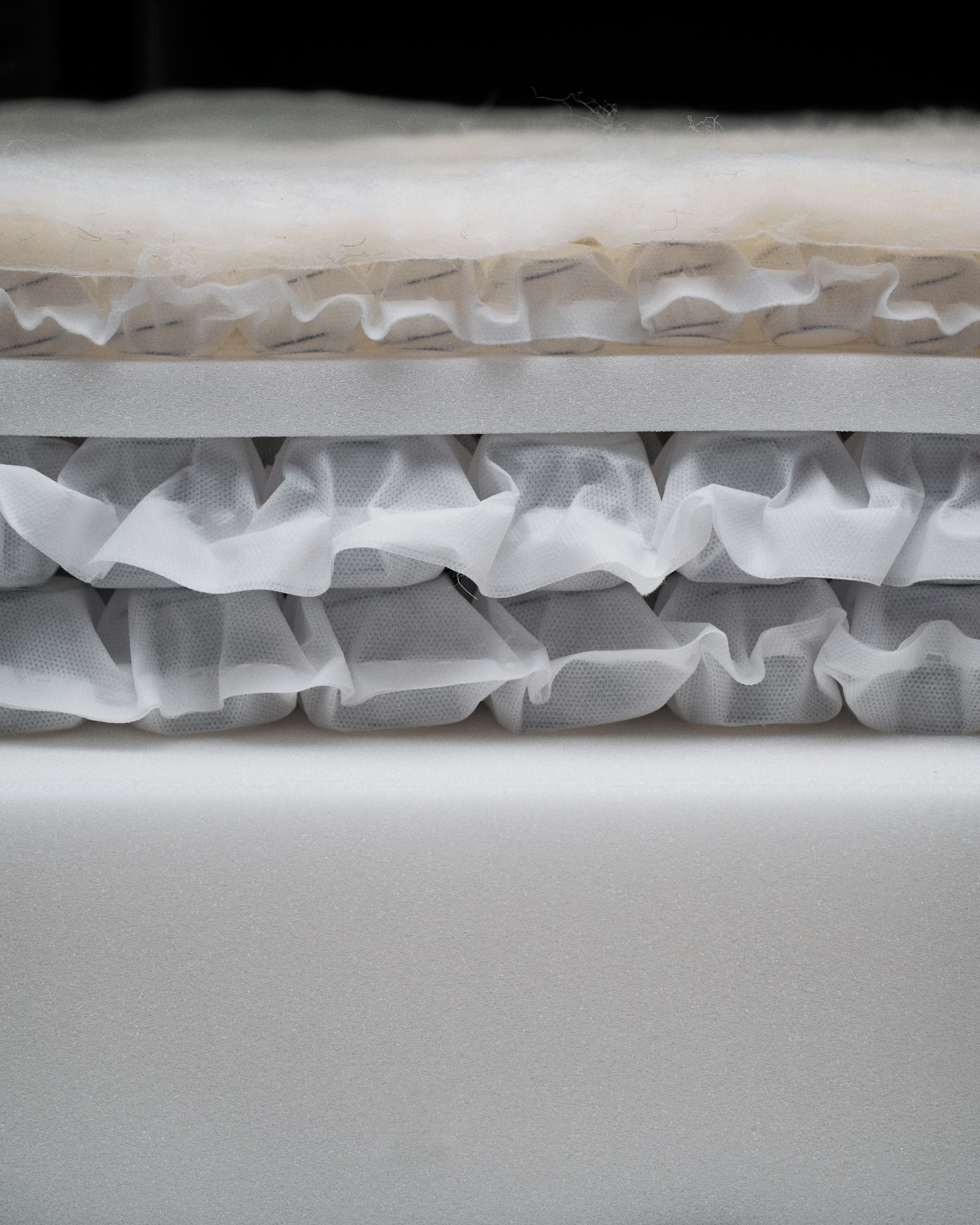 Cross-section of a Drift mattress showing multiple layers of springs, foam, and natural materials stacked horizontally.