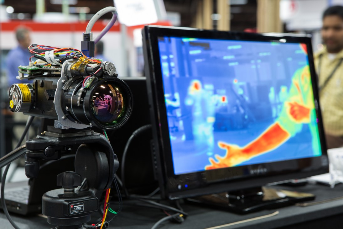 Teledyne Brown Engineering thermal camera mounted on display with heat-signature monitor showing building layout.