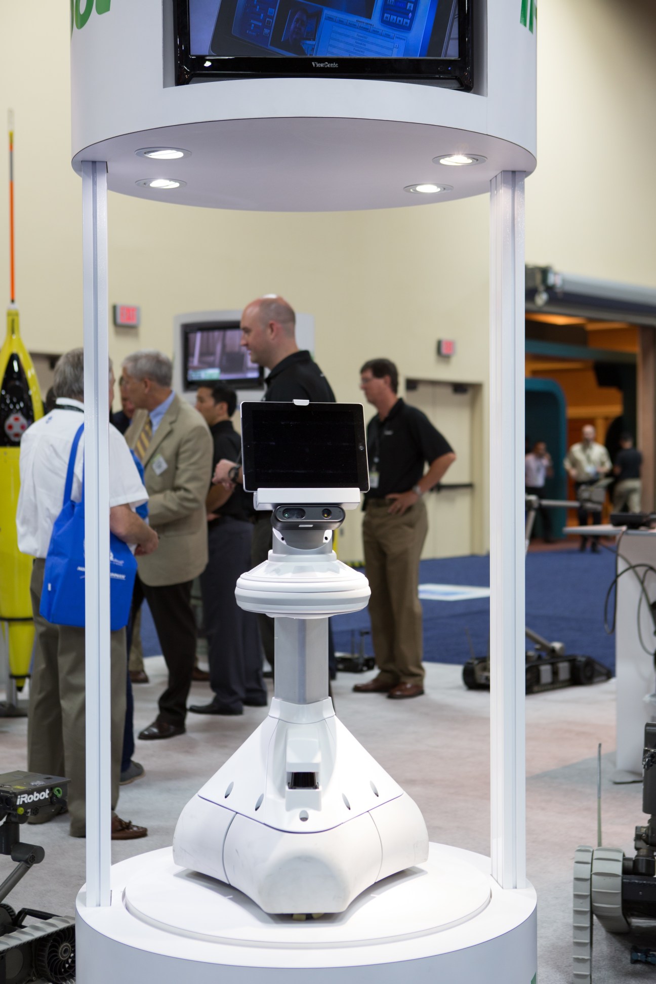 The Ava android by iRobot on display at a trade fair, featuring a white base with an iPad screen mounted on top.