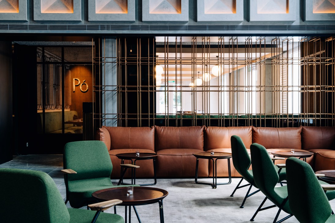 Restaurant Pó interior with brown leather seating, green armchairs, and brass lattice dividers at The Warehouse Hotel.