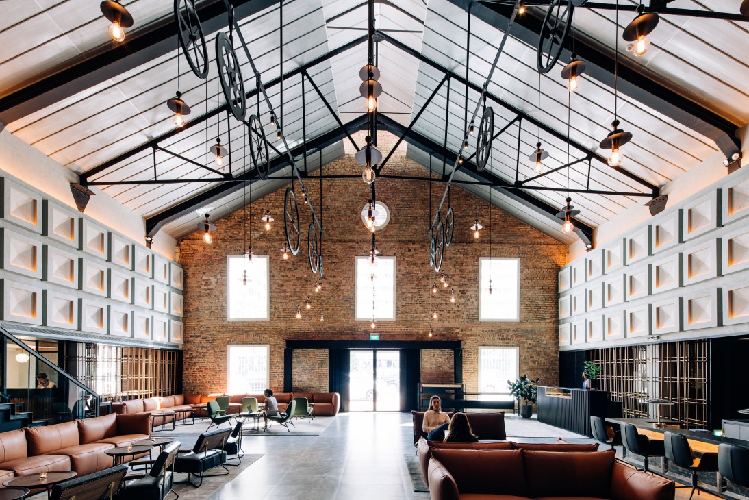 Warehouse Hotel reception with pulley-and-wheel light installation by Asylum spanning the vaulted ceiling