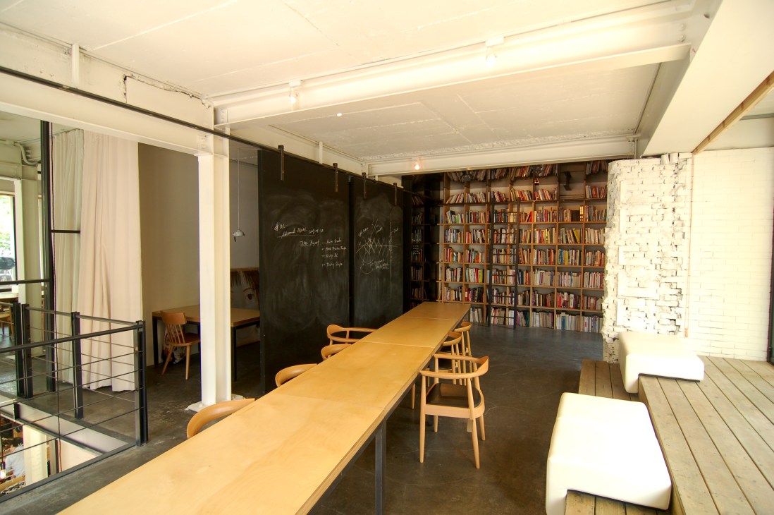 Interior of Tasting Room in Seoul showing long wooden table with chairs, bookshelves, and black chalkboard walls.