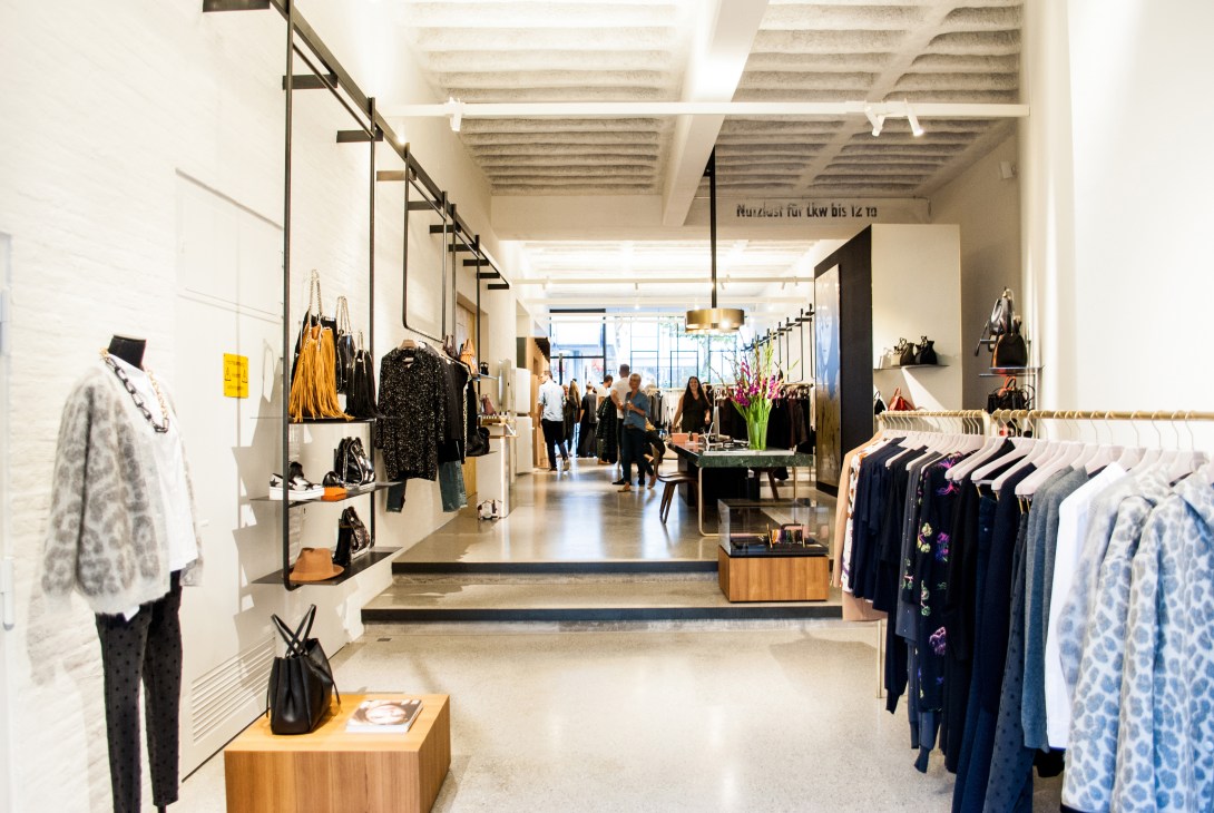 Interior of Bungalow womenswear store in Stuttgart with clothing racks, concrete floors, and brass lighting fixtures.