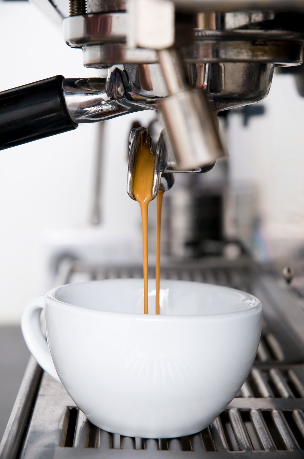 Espresso machine pouring a shot of coffee into a white cup.