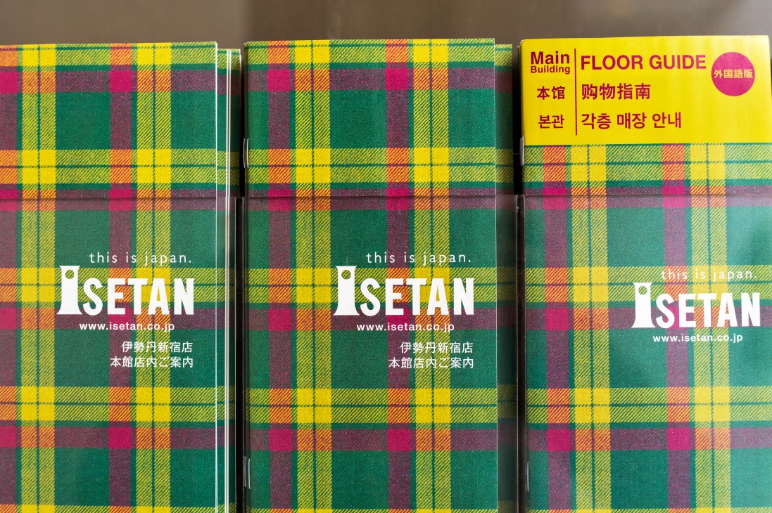 Isetan store floor guide brochures and shopping bags featuring the store's iconic tartan pattern in green, yellow, pink and purple.