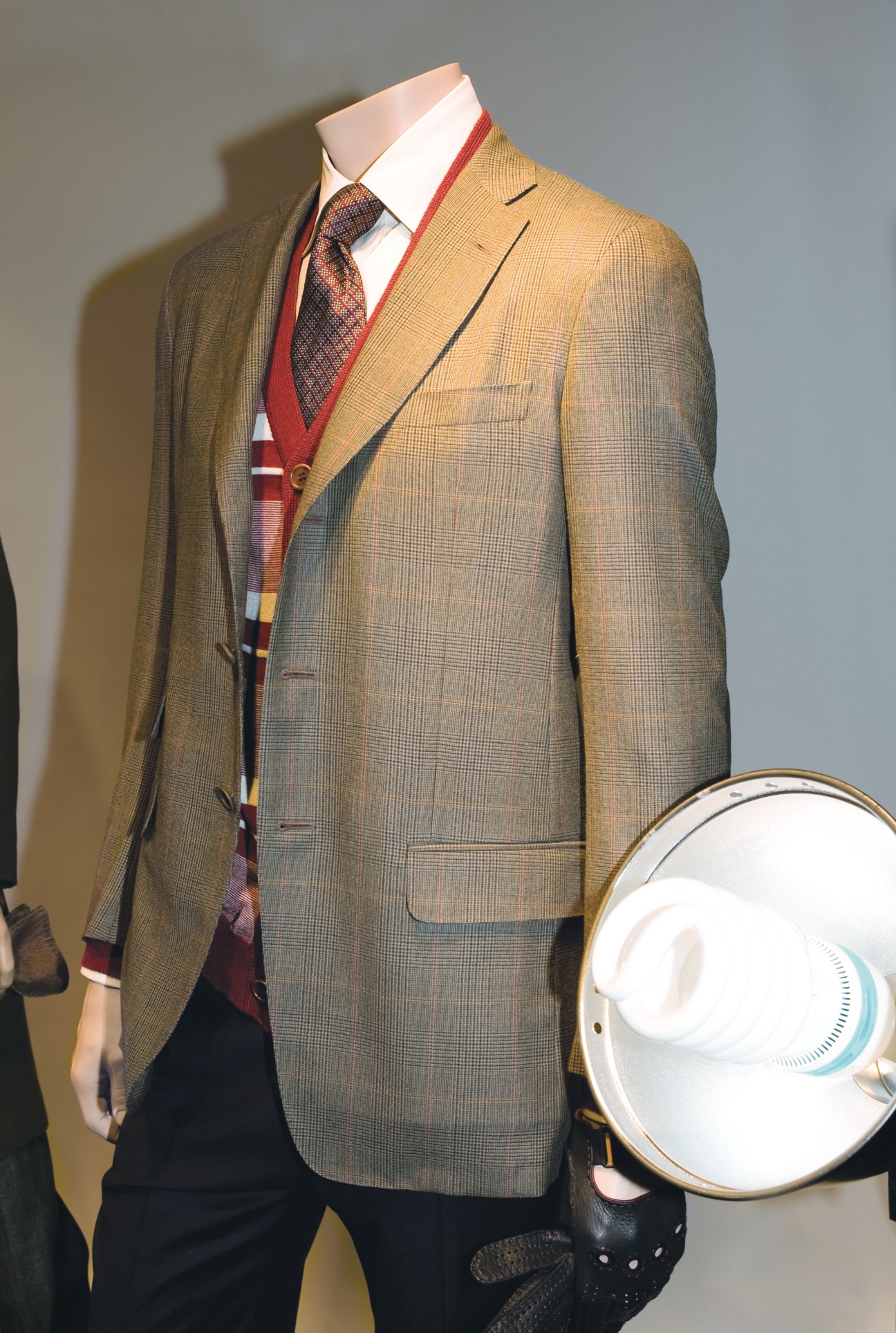 Mannequin displaying Dunhill tailoring with tan checked blazer, white shirt, red tie and striped scarf.