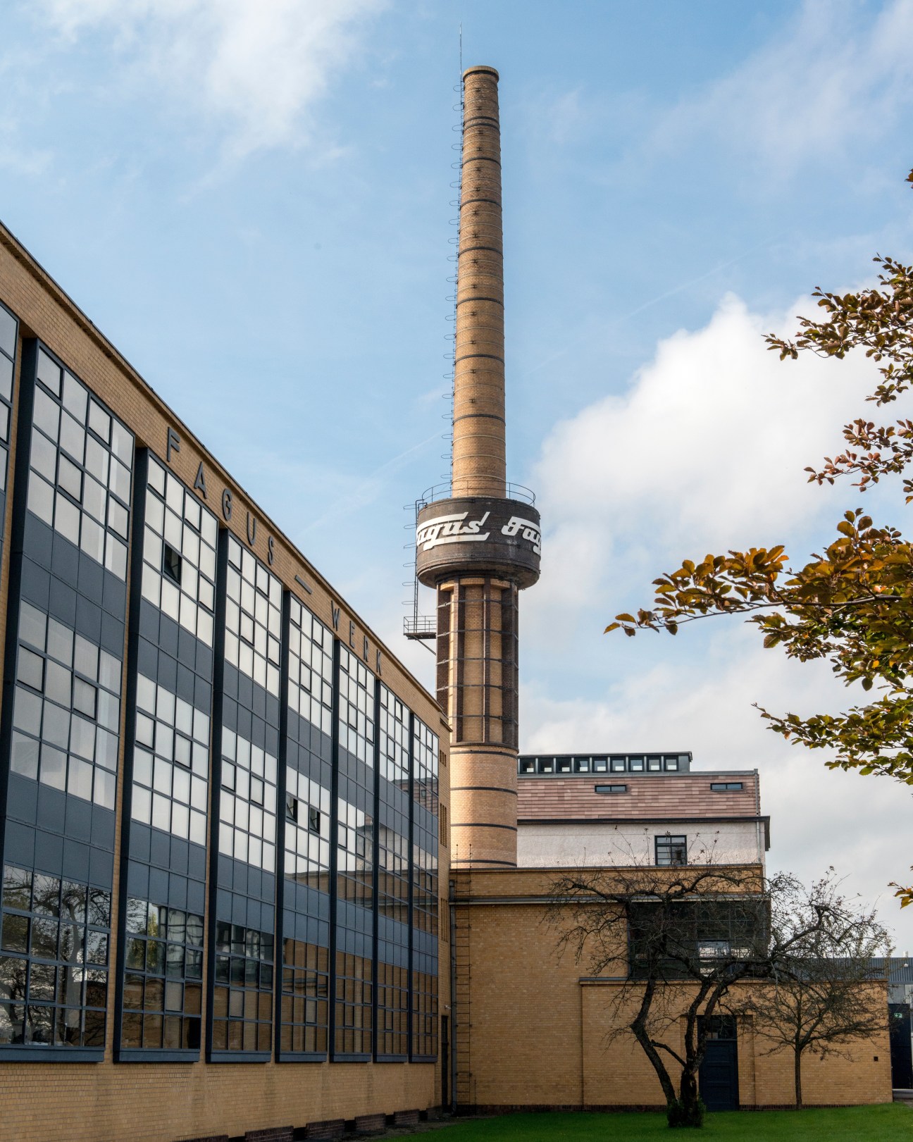 Fagus factory exterior featuring Gropius-designed modernist building with extensive gridded windows and tall brick chimney.