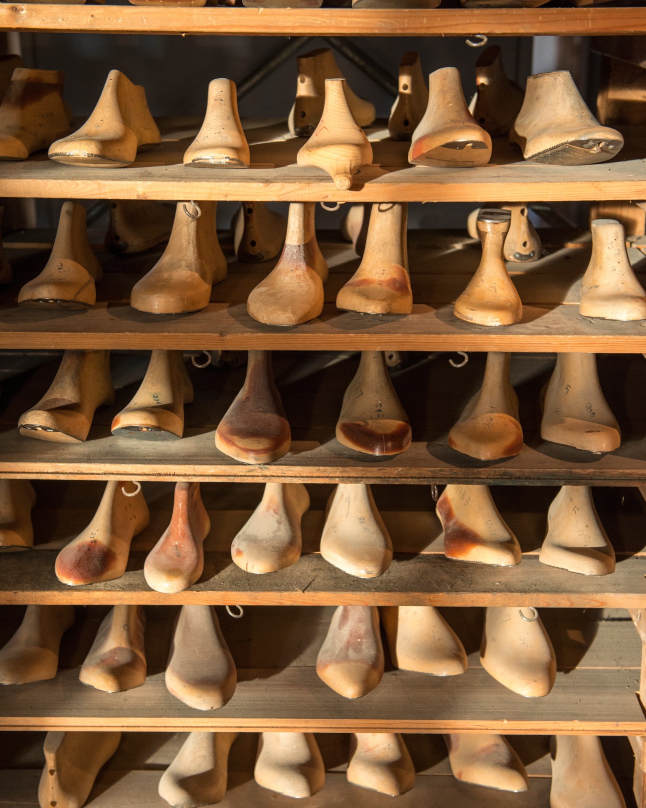Wooden shoe lasts in various sizes and widths displayed on wooden shelves at Fagus factory.