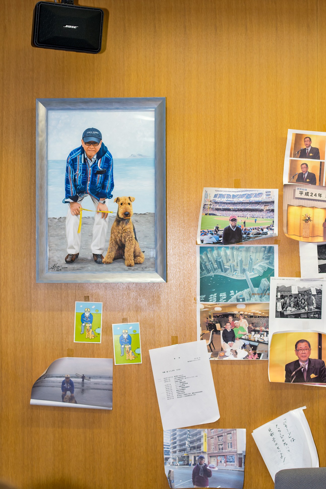 Wood-paneled office wall covered with framed and unframed photographs, personal mementos, and documents.