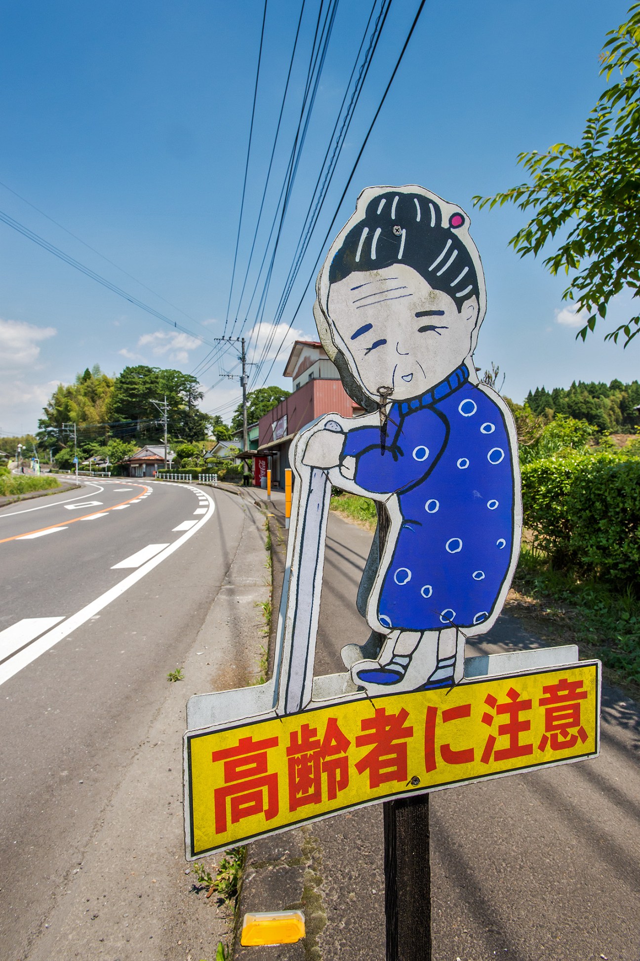 A cartoon street sign with a elderly woman figure in blue clothing alerts drivers to a retirement home.