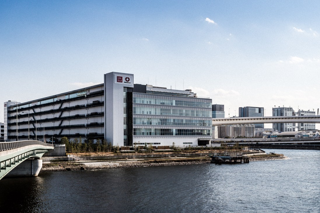 Uniqlo City headquarters building on Tokyo's Ariake waterfront with modern architecture and floor-to-ceiling windows.