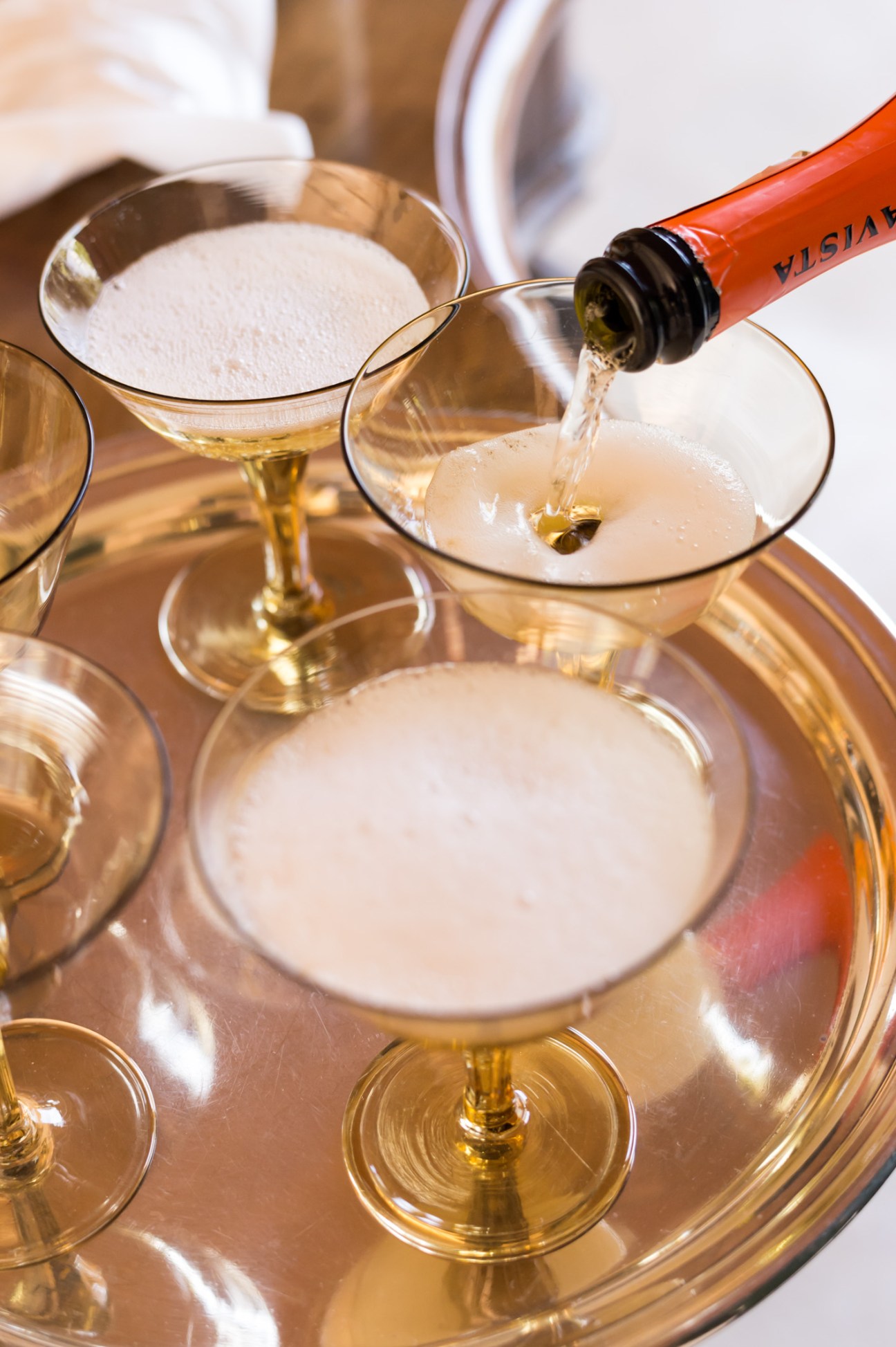 Franciacorta sparkling wine being poured into antique Venini glasses with foamed tops.