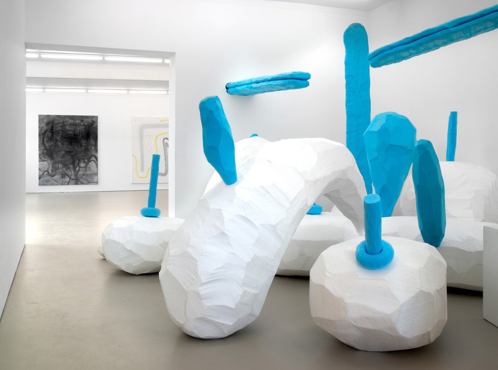 Contemporary art installation with white sculptural forms and bright blue abstract elements in a minimalist gallery space.