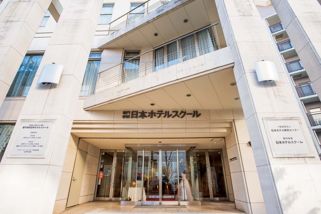 Exterior facade of Japan Hotel School building in Tokyo with Japanese signage above the entrance.