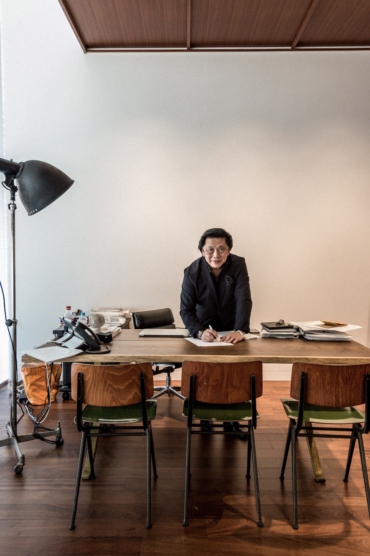 John Jay, president of global creative at Fast Retailing, seated at his desk in a minimalist office with wooden chairs and artwork.