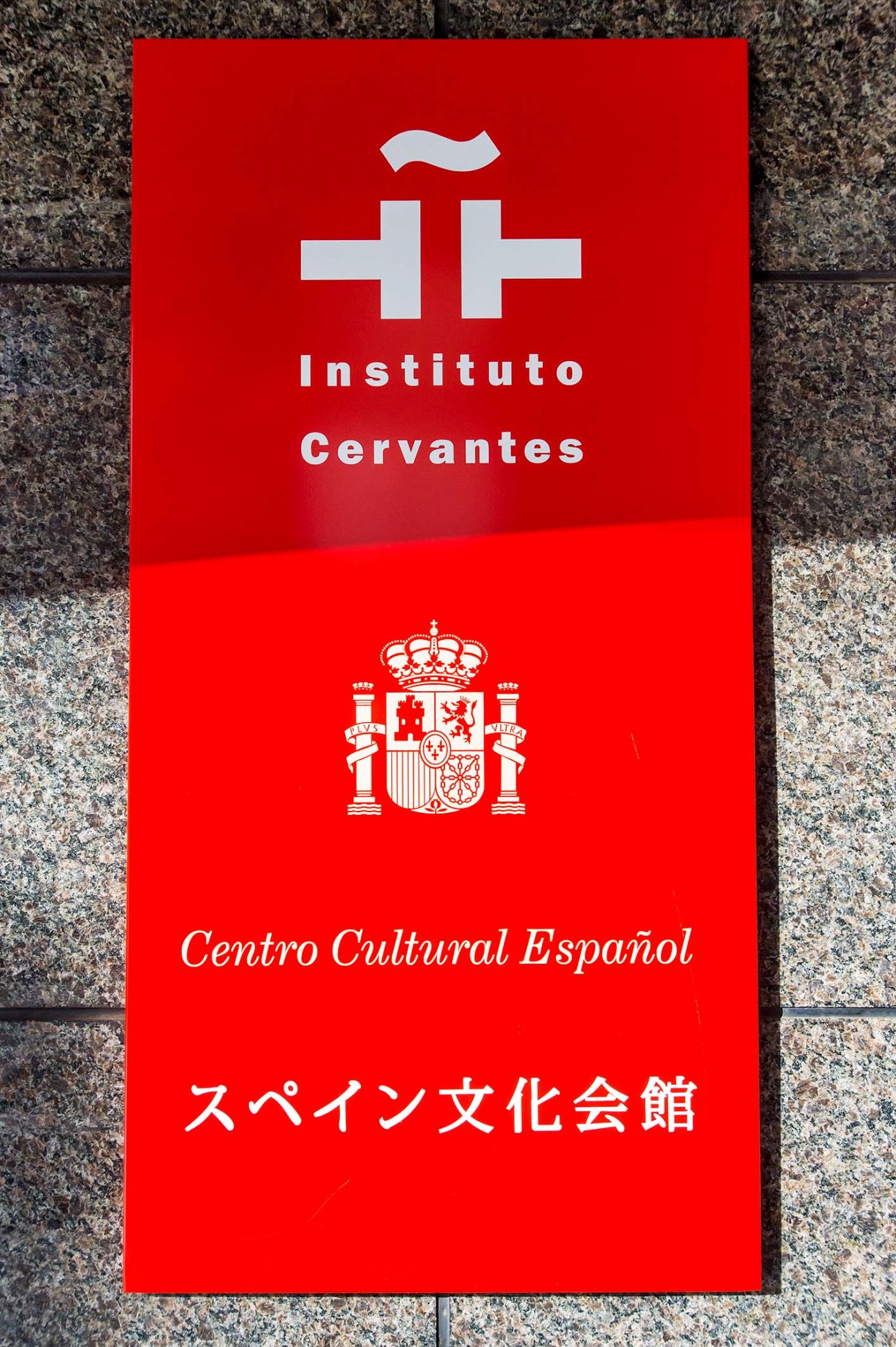 Red signage for Instituto Cervantes Tokyo displaying the organization's logo, Spanish coat of arms, and Japanese text.