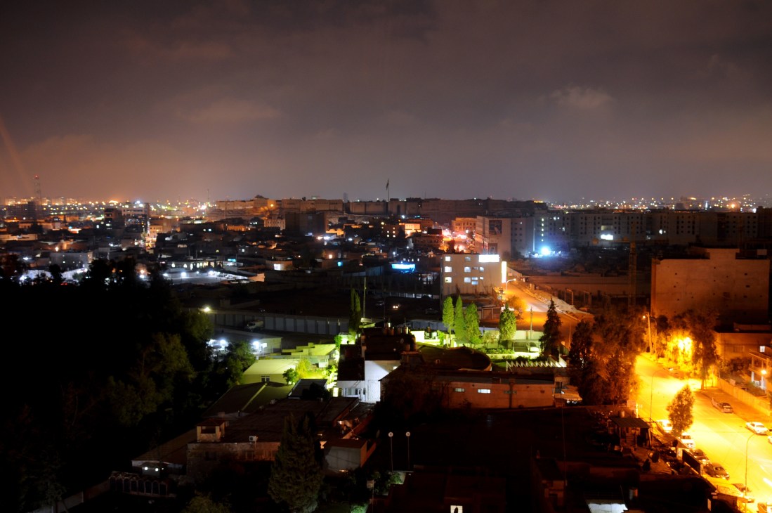 Arbil cityscape at night with illuminated buildings and the ancient citadel visible in the distance.