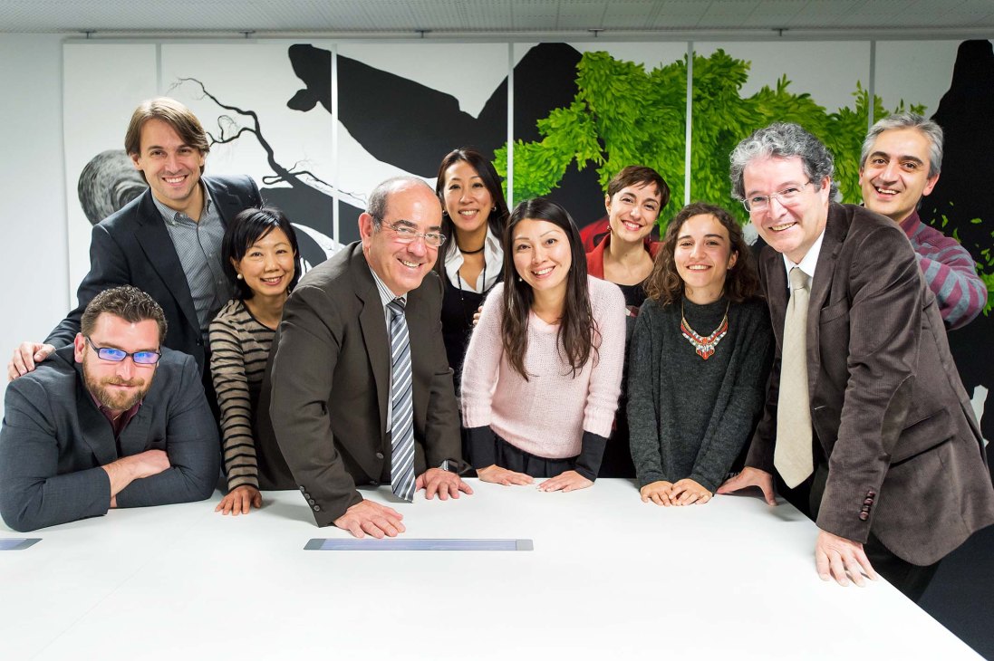 Spanish and Japanese staff members posing together at a table at Tokyo's Instituto Cervantes office.